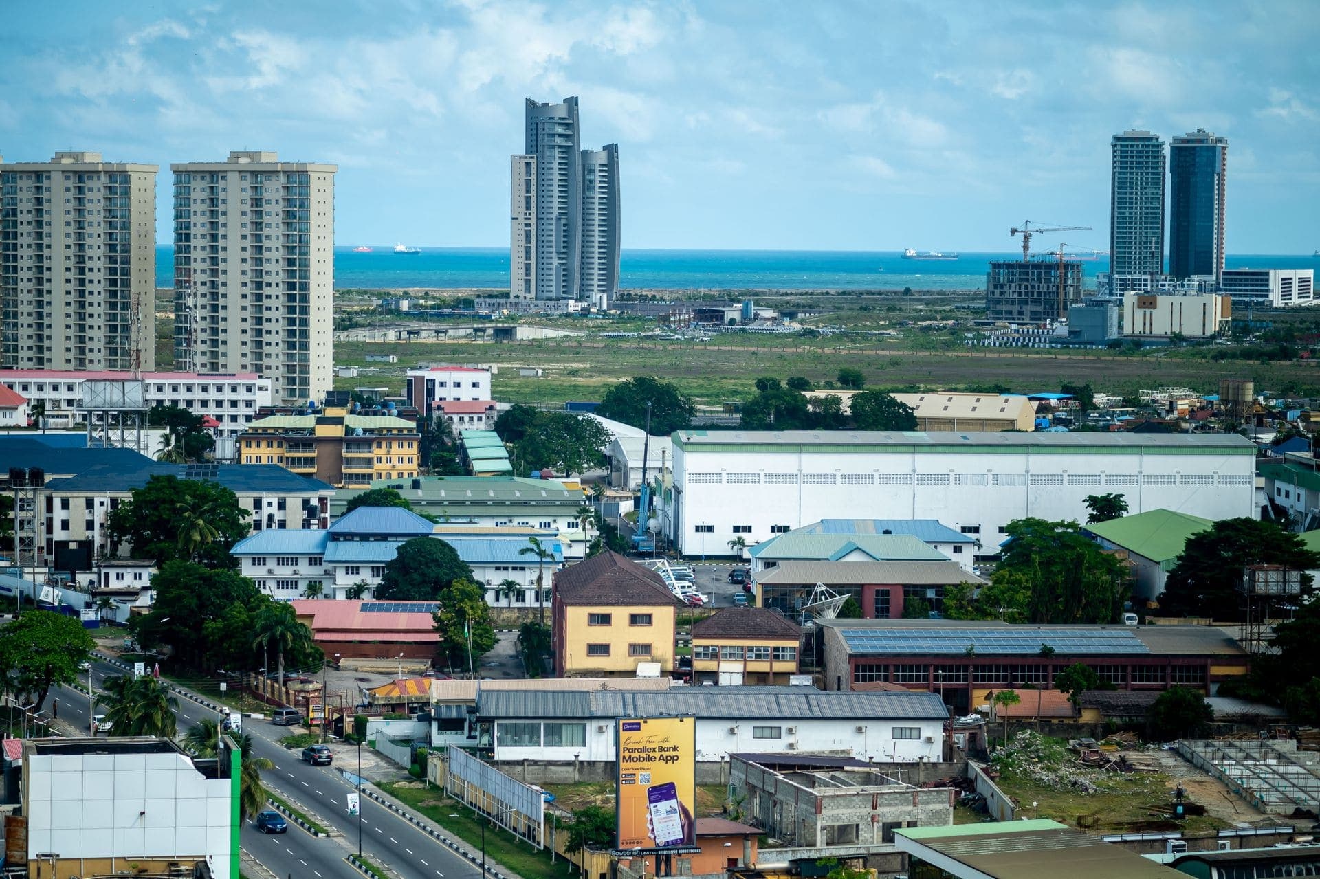Modern residential apartment towers on the Lagos skyline, with the Atlantic coastline behind them