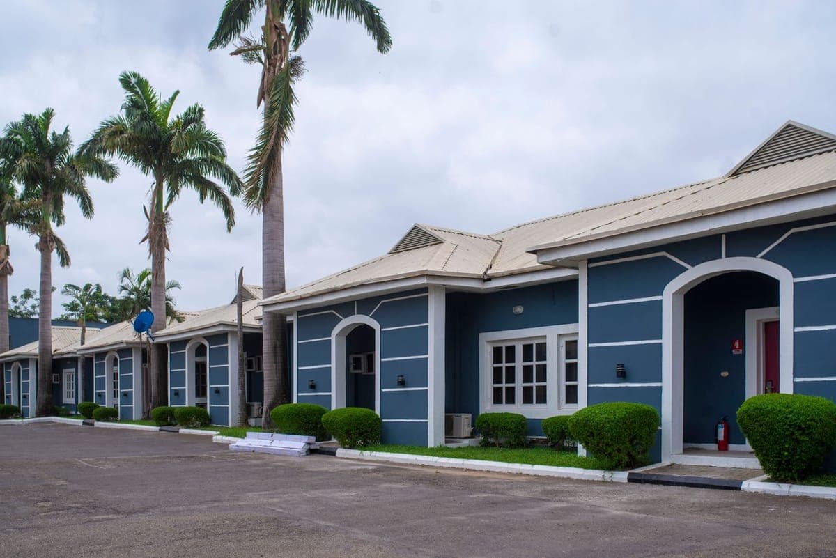 Row of low-rise apartments with arched entrances and palm trees